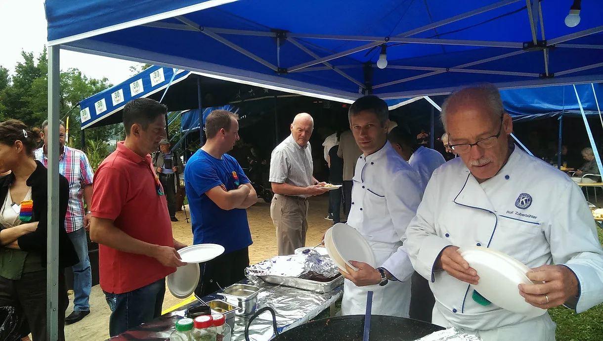 Clubmitglieder in Kochjacken schöpfen im Festzelt das Essen für die Gäste